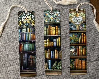 Può includere: Tre segnalibri rettangolari con un design a vetrata. Ogni segnalibro presenta un'illustrazione di libreria con un nappa attaccata. I segnalibri sono su una superficie grigia con occhiali.