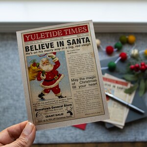Pu&ograve; includere: Un ritaglio di giornale in stile vintage con un'illustrazione rossa e bianca di Babbo Natale che porta un sacco di regali. Il titolo recita "Credi in Babbo Natale" e il testo descrive il viaggio di Babbo Natale per consegnare i regali la vigilia di Natale. Il giornale pubblicizza anche un negozio locale chiamato "Hometown General Store" con una vendita di articoli natalizi.