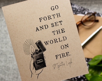 Può includere: Un biglietto marrone con il testo "Go Forth and Set the World on Fire." Il biglietto presenta un'illustrazione in bianco e nero di una mano che tiene un accendino con il testo "Congrats Graduate!" sul lato. Il biglietto è firmato "St. Ignatius Loyola."
