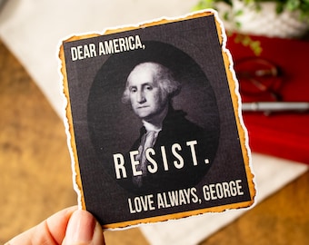 May include: Rectangular sticker with a black background and a portrait of George Washington. The text "DEAR AMERICA, RESIST. LOVE ALWAYS, GEORGE" is printed in white. The sticker has a distressed, burnt-edge design.