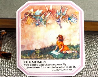 May include: A sticker with a pink border featuring a scene from Peter Pan. It depicts a girl in an orange dress looking up at fairies. The text reads "THE MOMENT you doubt whether you can fly, you cease forever to be able to do it."