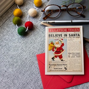 Pu&ograve; includere: Un ritaglio di giornale in stile vintage con un'illustrazione di cartone animato di Babbo Natale che porta un sacco di regali. Il titolo recita "YULETIDE TIMES CREDI IN BABBO NATALE &Egrave; in viaggio su una grande slitta rossa". Il testo include anche "Che la magia del Natale riempia il tuo cuore" e "Hometown General Store GRANDE SALDO Risparmia fino al 70% sugli articoli natalizi".