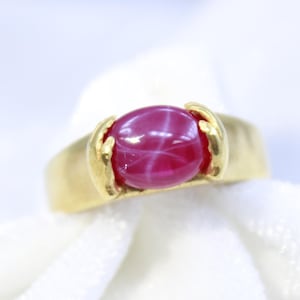 Peut inclure: Une bague en or avec une pierre précieuse en rubis étoilé rose.