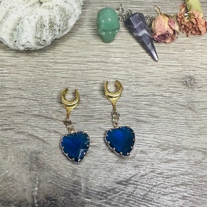 May include: A pair of gold crescent moon earrings with blue heart-shaped crystal accents.