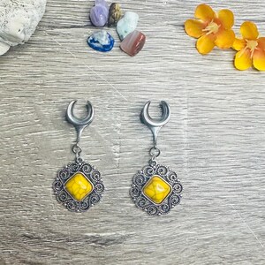 May include: A pair of silver ear gauges with a crescent moon design and a yellow stone set in a filigree pendant.