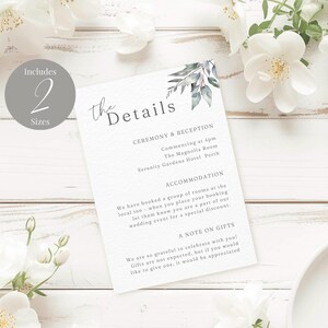 Könnte beinhalten: Eine weiße Hochzeitsdetailkarte mit Text und einem Aquarell-Blattdesign. Die Karte enthält Informationen über die Zeremonie, den Empfang und die Unterkunft. Die Karte erwähnt auch Geschenke. Umgeben von weißen Blumen.