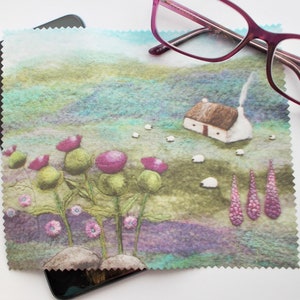 May include: A green and purple microfiber cleaning cloth featuring a charming illustration of a cottage, sheep, and wildflowers. The cloth is designed for cleaning glasses and screens.