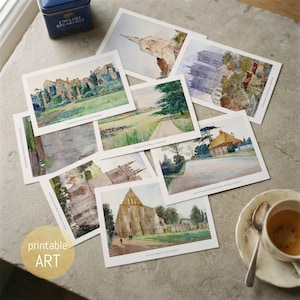 Puede incluir: Una colección de láminas de arte rectangulares con ilustraciones en acuarela de diversos edificios históricos y paisajes, cada una con etiquetas de texto impresas. Las láminas están dispuestas de forma dispersa junto a una taza de té y una lata azul.