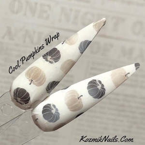 May include: Two white nail wraps with a pattern of brown and black pumpkins. The wraps are labeled "Cool Pumpkins Wrap".