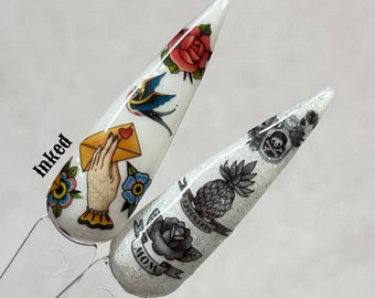 May include: Two white nail tips with different tattoo designs. The first nail tip has a hand holding a letter, a bird, a rose, and a flower. The second nail tip has a pineapple, a skull, a rose, and the word "MOM". The word "inked" is written on the left side of the image.