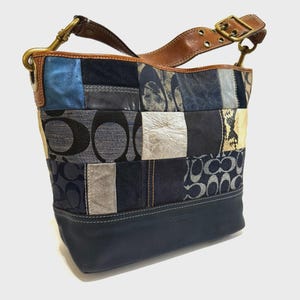Könnte beinhalten: Eine Patchwork-Umhängetasche mit einem braunen Lederriemen und goldfarbener Hardware. Die Tasche verfügt über eine Vielzahl von Stoffen in Blau-, Grau- und Silbertönen, darunter Denim und Leder. Der Boden der Tasche ist aus marineblauem Leder.