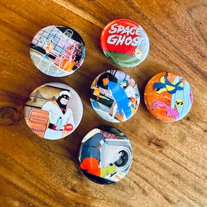 May include: Six round pinback buttons featuring characters from the animated television series Space Ghost. The buttons are colorful and feature various scenes from the show. The buttons are approximately 1 inch in diameter.