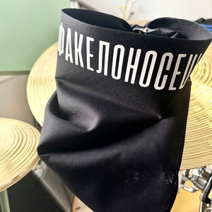 May include: Black bandana with the text "ФАКЕЛОНОСЕЦ" in white lettering.