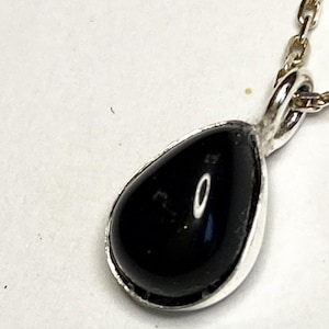 May include: A silver necklace with a teardrop-shaped black gemstone pendant.