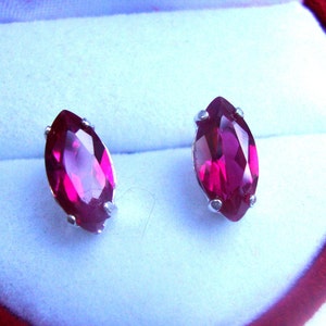 Puede incluir: Un par de pendientes de plata con piedras preciosas de color rosa brillante en forma de marquesa.