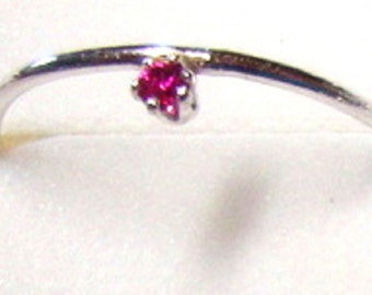 Op de afbeelding: Een zilveren ring met een kleine, felroze edelsteen.
