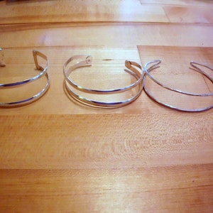 May include: Three silver bracelets, two with a double band design and one with a single band.
