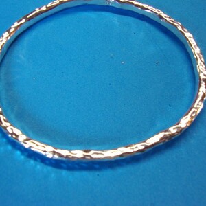 Puede incluir: Un brazalete de plata con un acabado texturizado martillado.