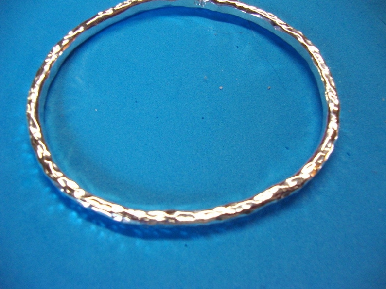Puede incluir: Un brazalete de plata con un acabado texturizado martillado.