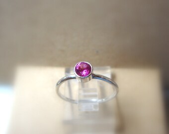 Op de afbeelding: Een zilveren ring met een enkele roze edelsteen in het midden.