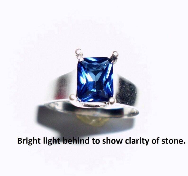 May include: A silver ring with a large, square-shaped, blue sapphire gemstone.