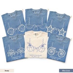 May include: A collection of blue jean and ivory t-shirts with various white graphic designs, including seashells, starfish, and flowers. Each shirt has a necklace and the text "Cassandra's bachelorette Key West, 2016".