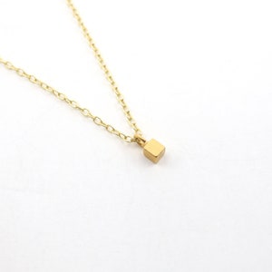 May include: A gold chain necklace with a small, square pendant.