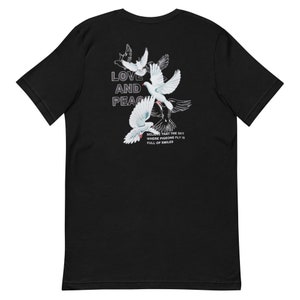 May include: Black t-shirt with a graphic of white doves flying and the text "LOVE AND PEACE" with the text "BELIEVE THAT THE SKY WHERE PIGEONS FLY IS FULL OF SMILES" underneath.