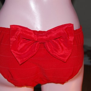 May include: Red satin underwear with a large bow in the back.