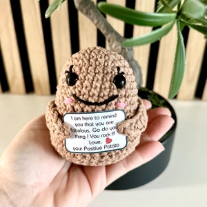 Könnte beinhalten: Ein gehäkeltes Kartoffelspielzeug, das eine Karte mit der Aufschrift "Ich bin hier, um dich daran zu erinnern, dass du fantastisch bist. Mach dein Ding! Du rockst !!! Liebe, deine Positive Kartoffel" hält.