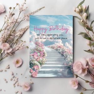 May include: A birthday card with a sky and cloud background, featuring a staircase lined with pink and white flowers. The card reads "Happy Birthday" and "I'm still celebrating you... just from a different place."