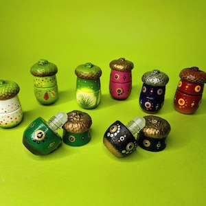 May include: A set of ten acorn-shaped roller bottles with various colorful designs. The bottles are painted with dots, stripes, and other patterns. The bottles are made of wood and glass and are perfect for essential oils or other liquids.