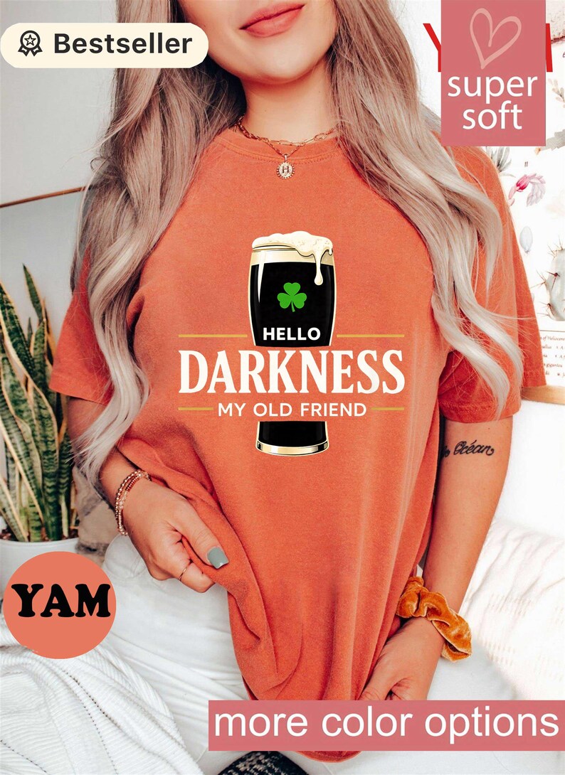 May include: Orange t-shirt with a graphic of a pint of dark beer with a shamrock and the words "Hello Darkness My Old Friend". The shirt has a "Bestseller" badge and "super soft" text.