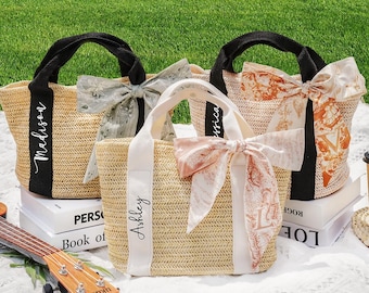 May include: Three woven straw tote bags with black handles and decorative bows. Each bag has a different ribbon design and a name printed on the front: Madison, Ashley, and Jessica. The bags are sitting on books and a white surface.