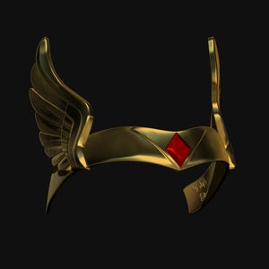 May include: A gold-coloured headpiece with wing-like accents and a red diamond-shaped gem in the centre. The headpiece has a curved design and is set against a black background. The item appears to be a costume accessory.