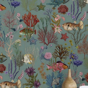 May include: A room with teal wallpaper depicting an underwater scene with colourful fish, coral, and starfish. A light yellow chest of drawers with black knobs and a framed botanical print are in the foreground. A pink armchair and a vase with flowers are also visible.