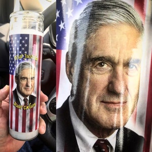 May include: A white candle with a red, white and blue American flag design. The candle features a portrait of a man with the text "Fiat Justitia" and "Ruat Coelum" printed on the front.