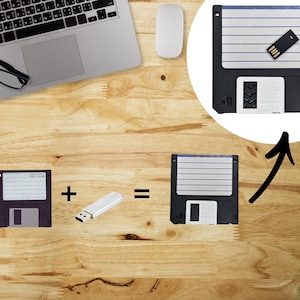 May include: Image showing a black floppy disk, a USB drive, and a combined floppy disk with a USB drive inserted. The image is on a wooden surface with a laptop, mouse, and glasses in the background.