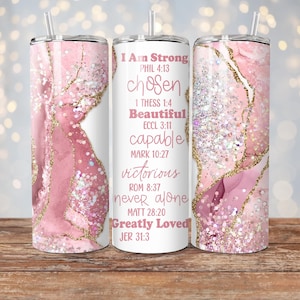 May include: A white tumbler with a pink and gold marble design and inspirational quotes. The tumbler features the text "I Am Strong", "chosen", "Beautiful", "capable", "victorious", "never alone", and "Greatly Loved" with corresponding Bible verses.