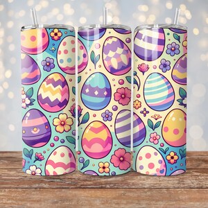 May include: Three stainless steel tumblers with a pastel Easter egg pattern. The tumblers are decorated with colorful eggs, flowers, and leaves on a light blue background.