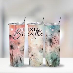 Op de afbeelding: Drie roestvrijstalen bekers met deksels en rietjes. Elke beker heeft een bloemenontwerp met paardenbloemzaden en de woorden "Just Breathe" in zwart schrift. De achtergrondkleuren zijn roze, perzik en blauwgroen.