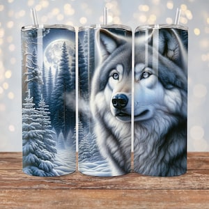May include: Three stainless steel tumblers with a wolf design. The wolf is gray and white and is looking to the right. The background of the tumbler on the left is a snowy forest with a full moon. The background of the tumblers on the right is a snowy forest.