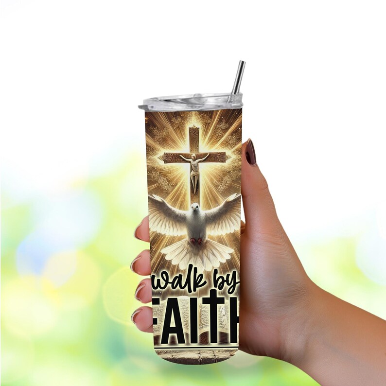 May include: A stainless steel tumbler with a religious design. The design features a cross with Jesus, a dove, and the words "walk by FAITH" in black. The tumbler has a silver straw and a clear lid. The background is a golden glow.