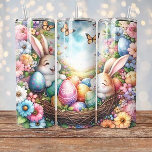 May include: A set of three stainless steel tumblers with a colorful Easter design. The tumblers feature bunnies, flowers, and Easter eggs in a nest.