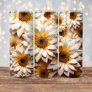 May include: A white and yellow sunflower pattern on a stainless steel tumbler. The tumbler has a straw and a lid.