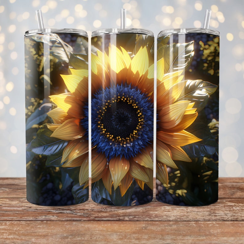 May include: Three stainless steel tumblers with a sunflower design. The sunflower is yellow with a blue center and is surrounded by green leaves. The tumblers are on a wooden surface.