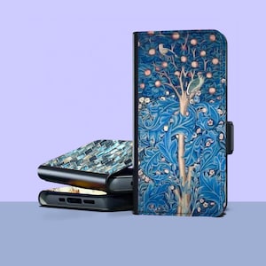 Puede incluir: Una funda de teléfono azul con un diseño de árbol con pájaros y frutas. La funda está abierta, revelando la pantalla del teléfono. Otra funda con un patrón de mosaico está apilada encima de una funda cerrada.