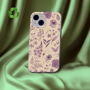 Puede incluir: Una funda para teléfono con fondo beige claro y un estampado botánico morado detallado de varias flores, hojas y helechos. La funda incluye un recorte para un sistema de cámara de doble lente y un símbolo de reciclaje verde arriba a la izquierda.