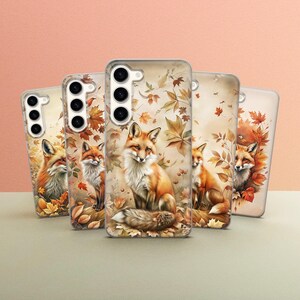 May include: Five phone cases with a fall theme. Each case features a different fox design with autumn leaves and a brown background. The cases are clear and show the phone's camera lens.