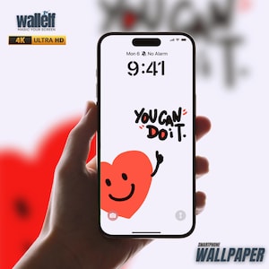 Könnte beinhalten: Ein Smartphone zeigt ein motivierendes Hintergrundbild mit dem Text "YOU CAN "DO IT." und einem roten Herz mit einem Smiley. Das Telefon wird in einer Hand gehalten.